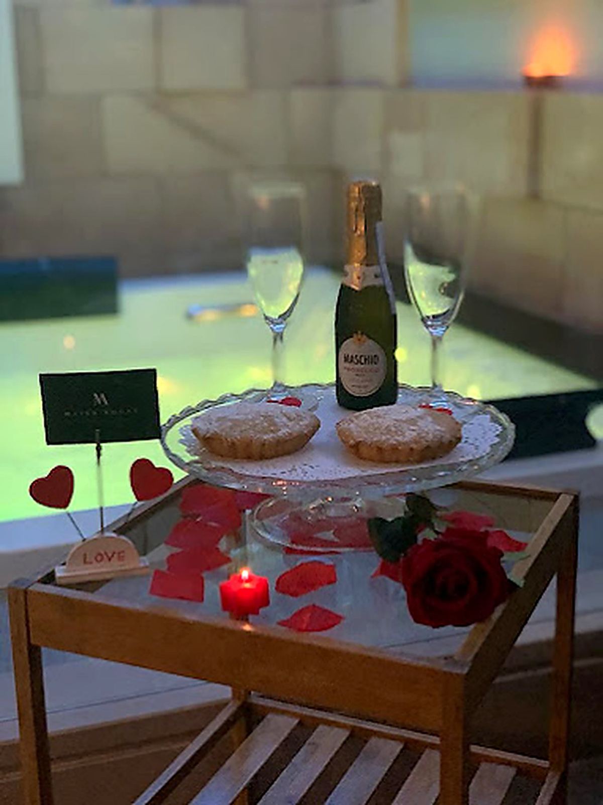 Bulles en suite : vin pétillant, verres et pâtisseries sur un plateau près de la baignoire balnéo