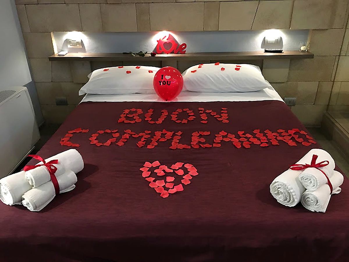 Le lit bordeaux avec un message d'anniversaire en pétales, un ballon et des serviettes nouées